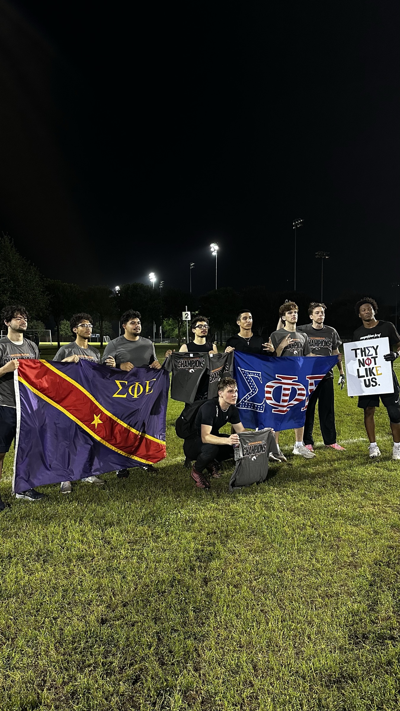 Intramural champions holding the SigEp flag on the field at night.